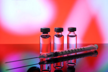 Small vaccine injection bottle transparent reflection refraction red led light background hypodermic...