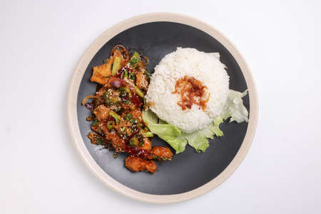 Chinese style Kung Pao Gong Bao Kung Po stair fried chicken with steamed rice lettuce on dark plate