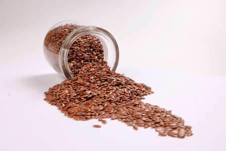 Flex seed flaxseed closeup pouring from small glass jar bottle sprinkled seedsの写真素材