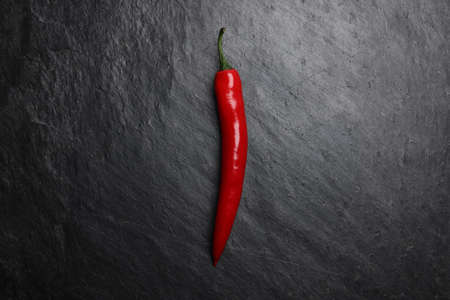 Red hot chilli pepper on dark black rough slate stone surface backgroundの写真素材