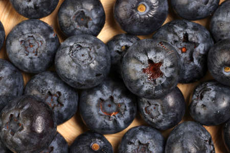 Fresh ripe deep purple Blueberry on old wooden plate macro closeup top viewの写真素材