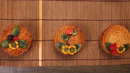 Colorful flower decorated mooncake Chinese mid autumn festival on bamboo food mat backgroundの写真素材