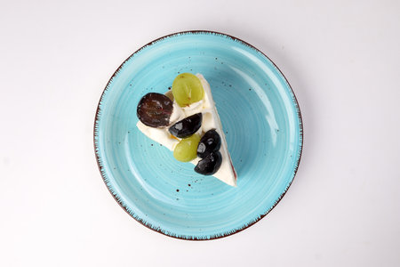 Green Black Grape Fruit cream layer cake on rustic blue plate over white backgroundの写真素材