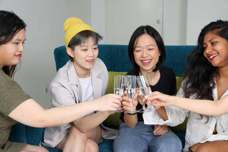 Young Asian woman group talk gossip chat sing drink cheers party fun enjoy emotion on blue living room sofaの写真素材