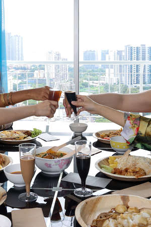 Young southeast asian woman group talk celebrate eating enjoying food rice curry noodle chicken drink cheers on dining tableの写真素材