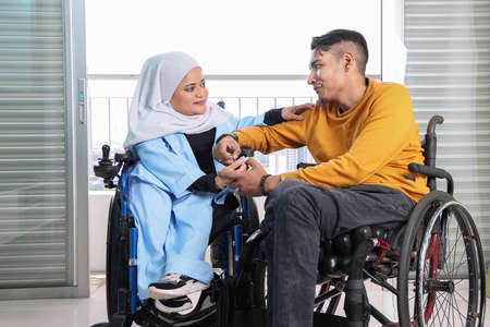 South east Asian malay man woman couple headscarf tudung middle aged disabled on wheelchair looking...