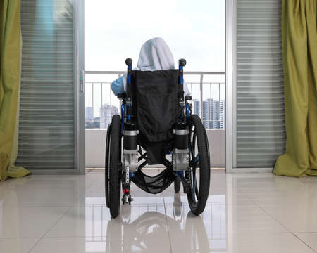 South east Asian malay headscarf tudung middle aged disabled woman on wheelchair looking sitting in...