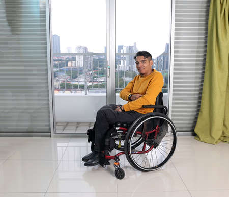 South east Asian malay middle aged disabled man on wheelchair looking sitting in front of balcony...