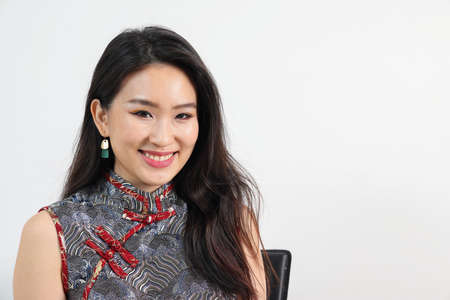 Beautiful young elegant southeast Asian woman wearing modern Chinese cheongsam dress pose smile look