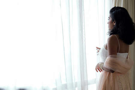 Beautiful young woman wearing Indian style royalty dress jewellery light makeup retro vintage fashionnext to window lightの写真素材