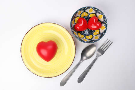 ceramic retro flower decorated food bowl and plate fork spoon with small big three dimension 3d red hart shape symbol on top of it white background copy text space top viewの写真素材