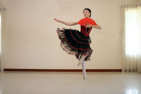 Beautiful Asian woman ballet dancer practice dance jump move wearing tutu at homeの写真素材