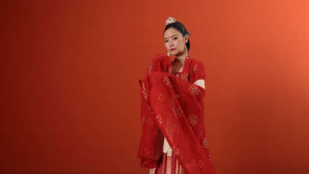 Young attractive Asian woman wearing tadeonal Chinese red hanfu long skirt dress costume scarf...