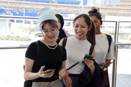 Four young attractive Asian group woman friends colleagues students talk walk discuss mingle...
