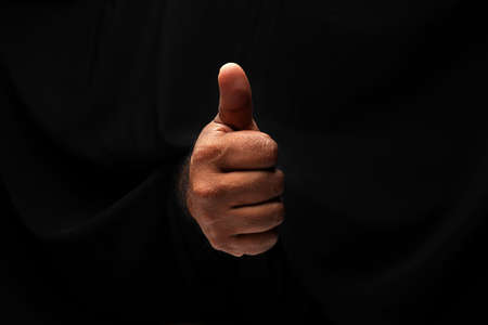 Asian male dark skinned single hand fist finger on black background thumbs up finger signの写真素材