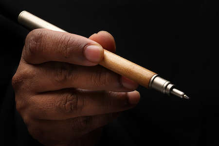 Asian male dark skinned single hand fist finger on black background holding pen write signの写真素材