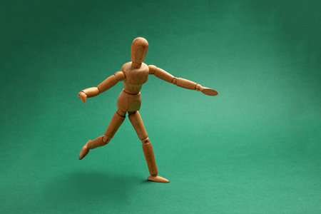wooden figurine doll playing miniature toy football soccer ball black and white colour over green background copy text space conceptの写真素材