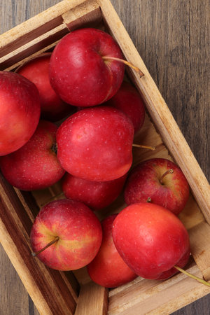 Small red Autumn Strawberry shaped Apple cut slice seed in wooden crate box on rustic wooden backgroundの写真素材