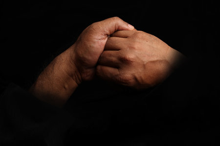 Asian dark skin top view two hand holding friendship unity sign on black backgroundの写真素材