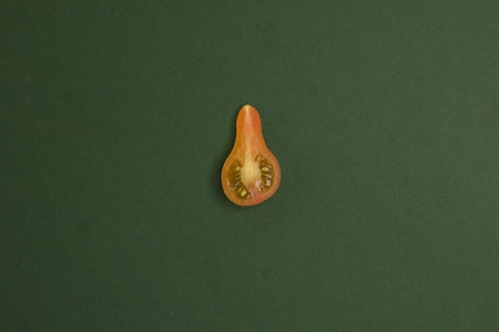 Small yellow red colourful pear tomato slice whole on gren background flat lay top viewの写真素材