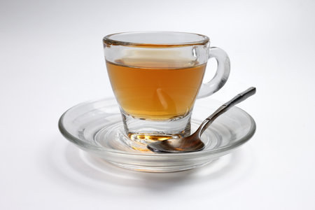 Hot tea in transparent glass cup saucer on white backgroundの写真素材