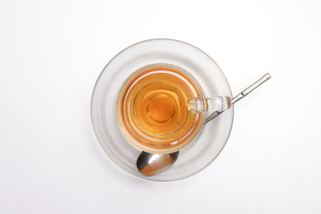 Hot tea in transparent glass cup saucer on white backgroundの写真素材