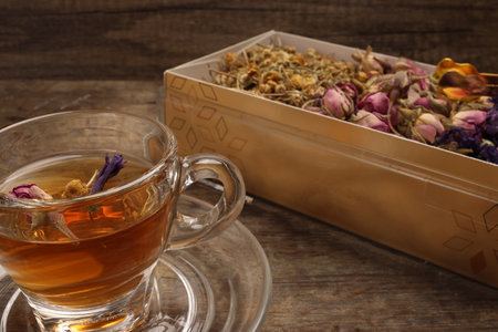 Dry flower tea rose bud butterfly pea chamomile flower transparent glass tea cup on rustic wooden table backgroundの写真素材