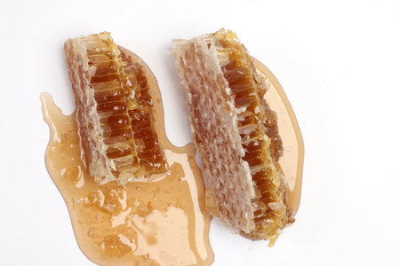 Sticky liquid honey natural geomatic hexagon honeycomb macro closeup on white backgroundの写真素材