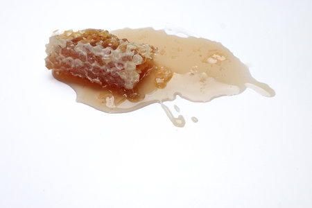 Sticky liquid honey natural geomatic hexagon honeycomb macro closeup on white backgroundの写真素材