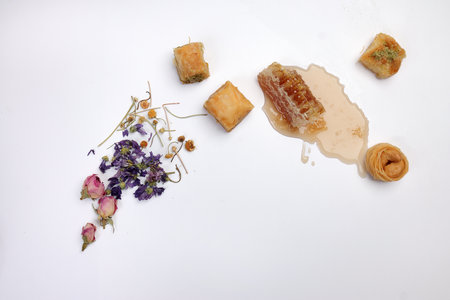 Layered stuffed pastry Baklava sweet dessert  date fruit liquid honey natural geomatic hexagon bee wax honeycomb  flower tea rose bud butterfly pea chamomile flower tea in transparent glass cup saucer on white backgroundの写真素材