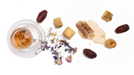Layered stuffed pastry Baklava sweet dessert  date fruit liquid honey natural geomatic hexagon bee wax honeycomb  flower tea rose bud butterfly pea chamomile flower tea in transparent glass cup saucer on white backgroundの写真素材