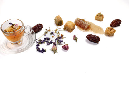 Layered stuffed pastry Baklava sweet dessert  date fruit liquid honey natural geomatic hexagon bee wax honeycomb  flower tea rose bud butterfly pea chamomile flower tea in transparent glass cup saucer on white backgroundの写真素材