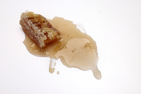 Sticky liquid honey natural geomatic hexagon honeycomb macro closeup on white backgroundの写真素材