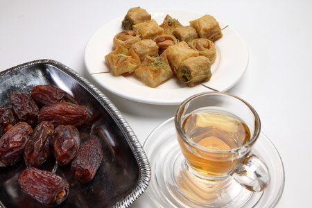 Layered stuffed pastry Baklava middle eastern sweet dessert dry ripe sweet date fruit tea in transparent glass cup saucer on white backgroundの写真素材