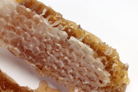 Sticky liquid honey natural geomatic hexagon honeycomb macro closeup on white background