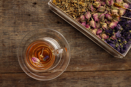 Dry flower tea rose bud butterfly pea chamomile flower transparent glass tea cup on rustic wooden table backgroundの写真素材