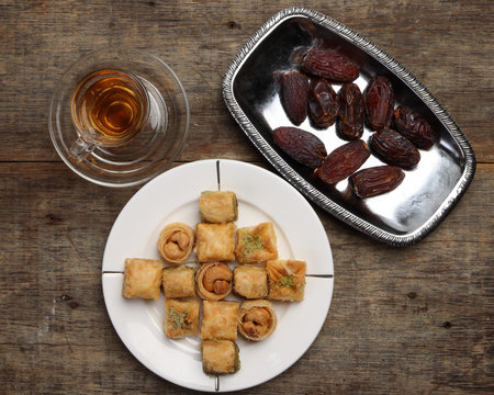 Layered stuffed pastry Baklava middle eastern sweet dessert dry ripe sweet date fruit tea in transparent glass cup saucer on rustic wooden backgroundの写真素材