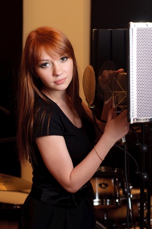 Girl singing to the microphone in a studioの写真素材