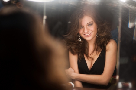 beautiful girl looking through the mirror in dressing roomの写真素材