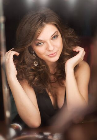 beautiful girl looking through the mirror in dressing roomの写真素材