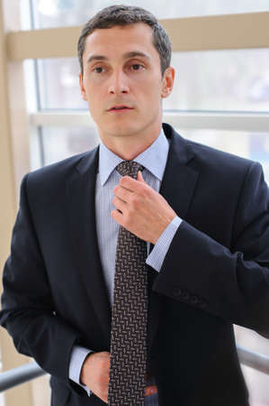 Manager corrects tie with a neutral facial expression の写真素材