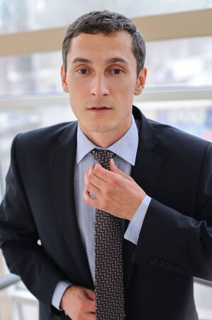 Manager corrects tie with a neutral facial expressionの写真素材