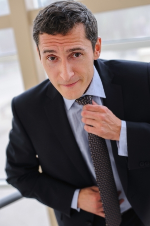 Manager corrects tie with a facial expression, implying a further showdownの写真素材