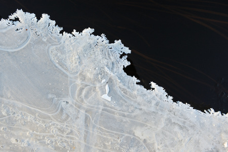 Thin transparent ice on the surface of the reservoir with dried grass and air bubbles under it.の写真素材