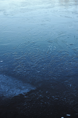 Thin transparent ice on the surface of the reservoir with dried grass and air bubbles under it.の写真素材