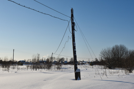 Rickety electric post frosty sunny day in a snowy field.の写真素材