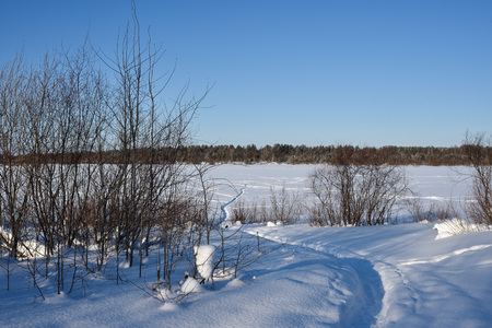 Path leading through the snow on the ice of the river frosty sunny day.の写真素材