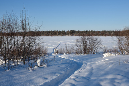 Path leading through the snow on the ice of the river frosty sunny day.の写真素材