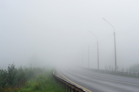 An empty road disappearing into the dense morning fog.の写真素材
