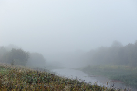Early autumn morning. Dense fog envelops the surface of the river.の写真素材